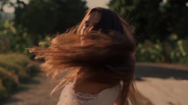 Zarif bir elbise giymiş bir kadın gün batımında canlı ve canlı tarlalarda zarifçe yürür.