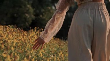 Nazik, şefkatli bir el zarif bir şekilde uzanır parlak, güzel bir tarlada açan sarı çiçeklere dokunmak için.