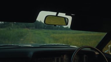 Bir aracın dikiz aynasından çarpıcı bir manzara, yolun ötesinde güzel ve geniş bir alanı ortaya çıkarır.