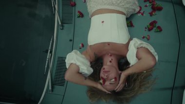 Canlı gül yapraklarıyla süslenmiş, derin ve zengin duygular taşıyan bir arabada zarif bir şekilde yatan bir kadın.