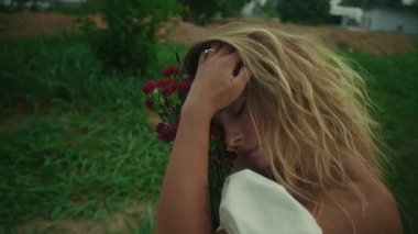 Bir kadın, güzelliği ve sükuneti özetleyen canlı çiçeklerden oluşan güzel bir bukete nazikçe bakar.