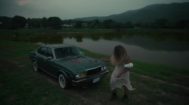 Günbatımında sakin bir gölün kenarında sakin sakin bir şekilde duran klasik bir arabayı gösteren rahatsız edici derecede güzel ve atmosferik bir sahne.