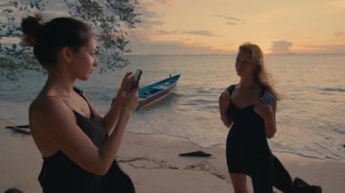 İki yakın arkadaş göz kamaştırıcı güzellikteki plaj günbatımında birlikte fotoğraf çekiyorlar.