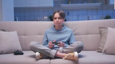 Koltukta oturan ve Dijital Konsolda Video Oyunlarında oynayan Yakışıklı Oyuncu Çocuk 'un Portresi. Heyecanlı Oyuncu Adam Video Oyunu için Joystick 'i kontrol ediyor. Bir kişi oturma odasında oyun oynamaya odaklanmış.