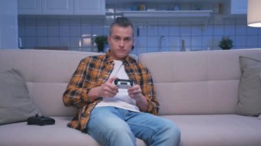 Bilgisayarda Video Oyunu Oynayan ve Modern Denetleyici Kullanan Bir Adam. Genç Adam Ekrana Bakıyor ve Oyun Alanı Joystick 'iyle Eğleniyor. Ev 'de Çekici Erkek Hobide Şans ve Zafer Kaybediyor