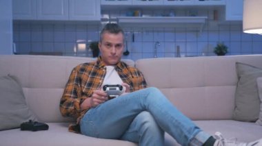 Bilgisayarda Video Oyunu Oynayan ve Modern Denetleyici Kullanan Bir Adam. Genç Adam Ekrana Bakıyor ve Oyun Alanı Joystick 'iyle Eğleniyor. Ev 'de Çekici Erkek Hobide Şans ve Zafer Kaybediyor