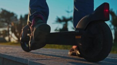 Man Rides Electric Kick Scooter ve Moves to Moves in Sunset. Geleneksel Trafikte Özgürlük İçin Geleceğin Moda Dengesi kavramı. Güneş Işığında Kiralık Tekmeleme Motoru Kullanan Adam 'ın Rekreasyonu