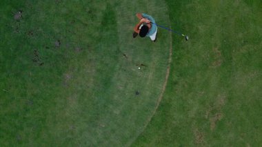 Golf sahasındaki sporcu oyun oynuyor ve Kulüp 'le topa vuruyor. Putter ve Tee 'de Golfball ile Atletik Kafkas Erkek Eğitimi. Cennetin Topraklarında Mutlu Aktif Profesyonel Kişinin Modern Kavramı