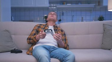 Bilgisayarda Video Oyunu Oynayan ve Modern Denetleyici Kullanan Bir Adam. Genç Adam Ekrana Bakıyor ve Oyun Alanı Joystick 'iyle Eğleniyor. Ev 'de Çekici Erkek Hobide Şans ve Zafer Kaybediyor