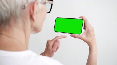 Yeşil Krom Anahtarlı Yaşlı Kişi Dokunma ve Geçiş Akıllı Ekran Telefonu. 50 'li yaşların kadın cep telefonunun tıkırdayan modeli. Konsept İzleme ve Gösterme Galerisi Sosyal Medya, Haber Oku, Uygulama