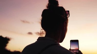 Summer Beach 'te oturan kadın cep telefonu kullanıyor ve okyanus doğasının fotoğrafını çekiyor. Yaz Tatili 'nde Akıllı Telefona Bakan Yetişkin Kız kavramı. Şafakta Sahil Kıyısı Cenneti Denizi Suyu