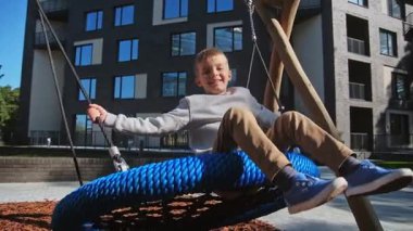 New House 'un Güzel Bahçesinde Gülümseyen ve Oynayan Mutlu Çocuk. Gülen Öğrenci Salıncakları Kullanıyor ve Yaz Tatili 'nde Eğleniyor. Sağlıklı Kafkas Çocuğu Ekoloji Bölgesi 'ndeki Banliyö evine taşınıyor