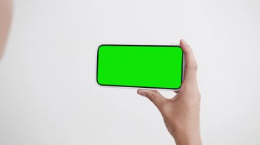 Yeşil Kroma Anahtarlı Genç Kadın Görüntü Akıllı Telefonu. 30 'lu yaşlarda cep telefonu modeliyle jest yapmış. Konsept İzleme ve Gösterme İnternet Sosyal Medya, Çağrılar, Haber Oku, Uygulama, Çok, Film