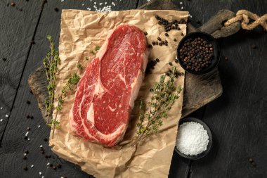 raw rib eye meat on bord over black background