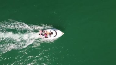 Mavi berrak sularda bir teknenin drone görüntüsü. Mavi denize giden beyaz bir teknenin üst görüntüsü. Sürat teknesi yüksek hızda hareket ediyor. Seyahat - görüntü. Yüksek kalite 4k görüntü