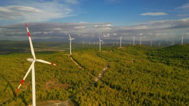 Aerial view of powerful Wind turbine farm for energy production on beautiful cloudy sky at highland. Wind power turbines generating clean renewable energy for sustainable development. 4k footage. High