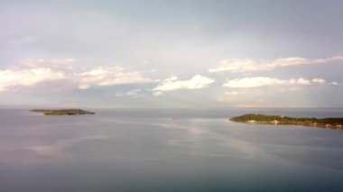 Denizde bir ada. Sakin mavi denizin ortasındaki yeşil tropikal adanın harika drone görüntüsü. Yüksek kalite 4k görüntü