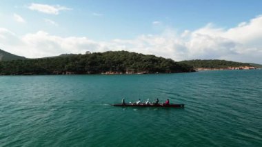 Dört kişilik bir ekiple birlikte sakin suda kürek çeken bir spor kanosu, Aerial view. Yüksek kalite 4k görüntü
