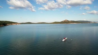 Aerial drone birds eye view video of sport canoe operated by young woman in emerald clear waters. High quality 4k footage