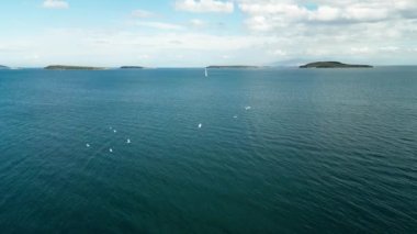 Güneş yatının havası yaşlılık denizinde yüzüyor. Açık denizde beyaz tekne. Güneş ışığında bulutlu bir yelkenliyle yaz gezisi. Urla izmir deniz kıyısı ve su taşımacılığı. - Evet. Yüksek kalite 4k görüntü