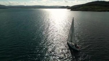 Güneş yatının havası yaşlılık denizinde yüzüyor. Açık denizde beyaz tekne. Güneş ışığında bulutlu bir yelkenliyle yaz gezisi. Urla izmir deniz kıyısı ve su taşımacılığı. - Evet. Yüksek kalite 4k görüntü