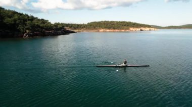 man rowing in the blue sea between mountains on a beautiful cloudy day. High quality 4k footage