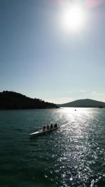 Dört kişilik bir ekiple birlikte sakin suda kürek çeken bir spor kanosu, Aerial view. Yüksek kalite 4k görüntü