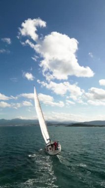 Güneş yatının havası yaşlılık denizinde yüzüyor. Açık denizde beyaz tekne. Güneş ışığında bulutlu bir yelkenliyle yaz gezisi. Urla izmir deniz kıyısı ve su taşımacılığı. - Evet. Yüksek kalite 4k görüntü