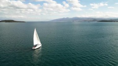 Aerial of sun yacht sail in agean sea. White boat at open sea. Summer cruise on sailboat at sunlight with clouds. urla izmir sea coast with water transport. . High quality 4k footage
