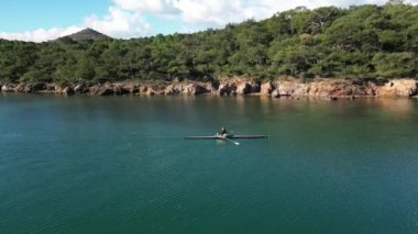 man rowing in the blue sea between mountains on a beautiful cloudy day. High quality 4k footage