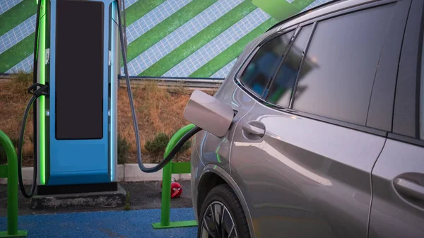 現代の技術と電気自動車のEv車への充電電力ケーブルポンププラグUi制御情報表示 車の給油所接続された電源ケーブル代替持続可能なエコエネルギー — ストック写真