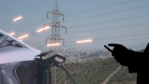 Man Ansluter Elbil Till Laddare Och Power Transmission Lines Bakgrunden — Stockvideo