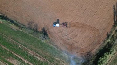 İnsansız hava aracıyla traktörün üzerinden uçmak harrow sistemli tarla sürme tarlası ekilmiş tarım arazisi, arkadaki toz tabakası yeni ekin ekimi için toprağı hazırlamak, tarım kavramı, üst görünüm.