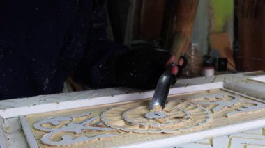Erkek Ellerinin Kapanışı, ahşap mobilyalara oyma. Marangoz, Artistik Ahşap oymacılığı için alet kullanıyor. Ahşap bir panelde keski ve çekiçle ahşap bir süs üretiyor. Yüksek kalite 4k görüntü