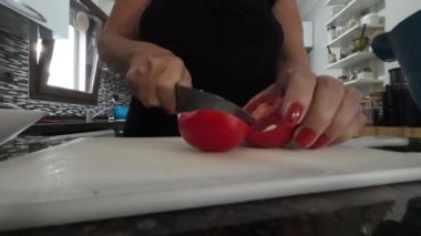 Mutfakta domatesleri doğrama tahtasında doğrayan bir kadın. Yüksek kalite 4k görüntü