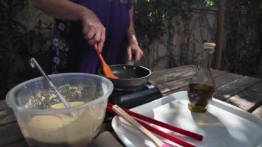 Kadın tavada pişmiş bir gözlemeyi diğer tarafa spatulayla fırlatıyor. Yüksek kalite 4k görüntü