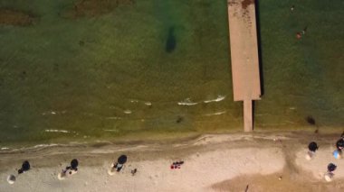 Sanatsal bir hava manzarası, çimenli bir arazinin yakınında suyla çevrili ahşap bir rıhtımı yakalar ve sakin ve güzel bir manzara yaratır.