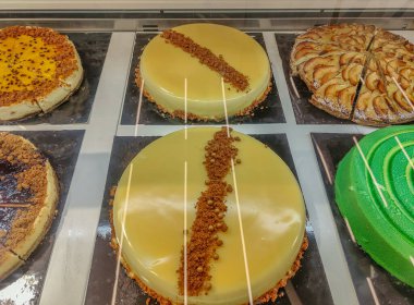 Elmalı turta, yeşil turta ve kahverengi turta ile çevrili lezzetli ve iştah açıcı sarı bir turtanın yakın çekimi. Doğum günleri ve özel partiler için lezzetli kekler..