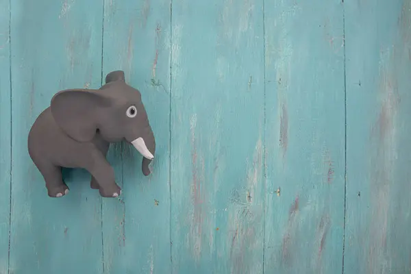 Little gray toy elephant on blue wooden vintage background. Ideal for copyspace