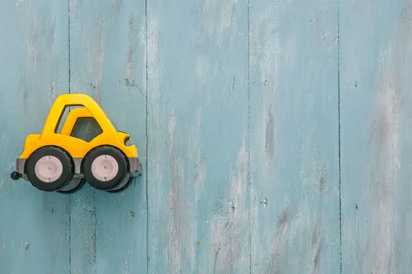Yellow toy vehicle. Vintage style turquoise blue wooden background with copy space