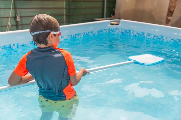 青いプールに長い水泳麺を持って立って 暖かく明るい晴れた日に泳ぐ準備をする少年 — ストック写真