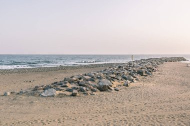 Kayalık bir kıyı şeridi ve sakin bir okyanusu olan bir sahil. Gökyüzü açık mavi bir renktir