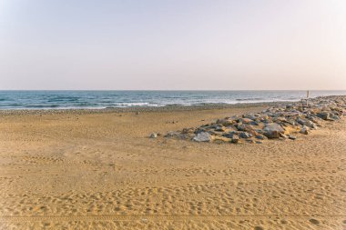 Kayalık bir kıyı şeridi ve sakin bir okyanusu olan bir sahil. Gökyüzü açık mavi bir renktir