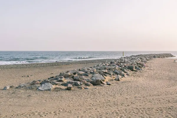 Kayalık bir kıyı şeridi ve sakin bir okyanusu olan bir sahil. Gökyüzü açık mavi bir renktir