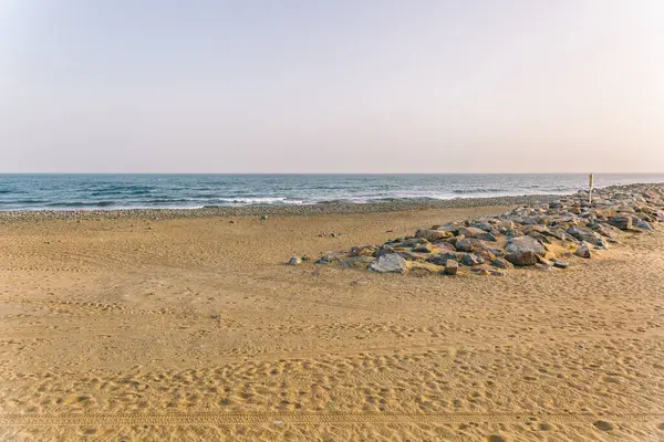 Kayalık bir kıyı şeridi ve sakin bir okyanusu olan bir sahil. Gökyüzü açık mavi bir renktir