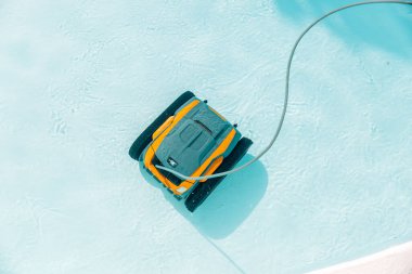 Bir robotik havuz temizleyicisi bir havuzun yüzeyinde yüzüyor. Havuz temiz ve robot işini yapıyor.