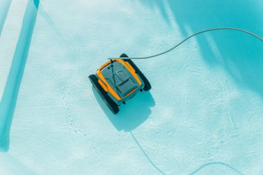 Bir robotik cihaz havuzda yüzüyor. Cihaz sarı ve siyah. Havuz mavi.