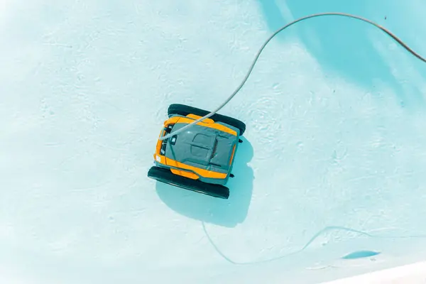 Bir robotik cihaz havuzda yüzüyor. Cihaz sarı ve siyah. Havuz yaz mevsiminde mavidir.