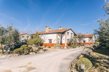 Ortasında beyaz bir ev olan bir dizi ev. Evlerin hepsi beyaz ve kırmızı süslemeli. Sokaklar ağaçlar ve çalılarla dolu.