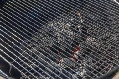 Üzerinde bir sürü kömür olan bir ızgara. Kömürler siyah, ızgara siyah.